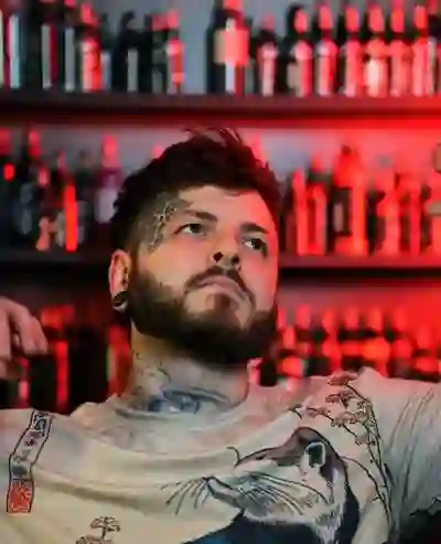 Alexander Kuzmin, co-owner of Requiem Tattoo Shropshire, bearded with neck tattoos, lit by dramatic red studio lighting